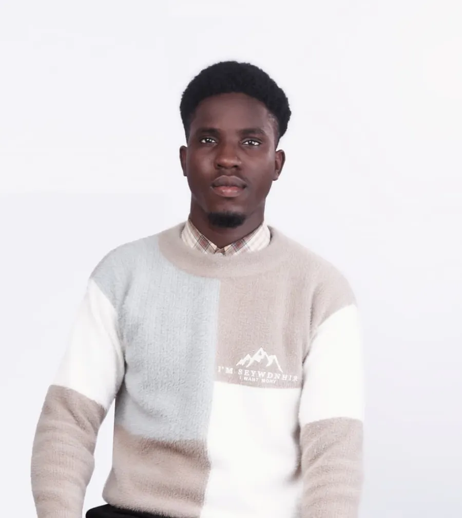 Dr Sales seated on a stool in a colour-block sweater